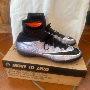 Nike mercurial superbly  fotbollsskor indoor - Snygga Nike fotbollsskor med högt strumpliknande skaft i svart och lila. Skorna har svart snörning, vit swoosh och mönstrad sula i lila och svart. Ovandelen är i syntetmaterial och designen är riktigt sportig och modern.   These are a old school pair and one legendary pair. Pick up a steel 