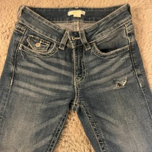 Blå broderade bootcut jeans - Snygga blå jeans från gina young med broderade detaljer och dekorativa knappar på bakfickorna. Jeansen har låg midja, bootcut-ben och slitningar framtill och endast använda. fåtal gånger 💞💞köpta för 400kr säljer för 200kr