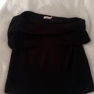 Svart stickad offshoulder topp Nelly - Nyköpt Slouchy neck knit top från Nelly. Aldrig använd men drog bort lappen av misstag så kan inte lämna tillbaka den. Storlek M💞🫶🏻 og pris 399kr mitt pris 299kr
