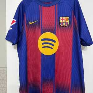 FC Barcelona Lamine Yamal matchtröja  - Säljer en  FC Barcelona matchtröja med Lamine Yamal och nummer 19 på ryggen. Tröjan är blå och röd med gula detaljer, har korta ärmar och är tillverkad i Dri-Fit material. Klassiska ränder, klubbmärke på bröstet och sponsorer som Spotify och UNHCR. Storleken är S men passar perfekt för M också 