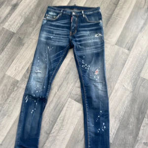 Dsquared2  jeans med slitningar - Snygga blå skinny jeans från Dsquared2 med coola slitningar och färgstänk. Jeansen har klassisk femficksdesign, låg midja och detaljerade sömmar. Materialet är jeans i bomull med en schysst tvättad look och patch på bakfickan.