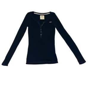 hollister topp - Långärmad marinblå henleytopp från äldre hollister i storlek s med supersöta detaljer vid knäppningen💙Har två små hål precis ovanför fållen, ett fram och ett bak, som definitivt går att laga, i övrigt mycket fint skick. Använd gärna köp nu🫶🏼