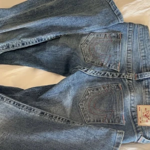 True Religion blå bootcut jeans - Säljer ett par blå jeans från True Religion med snygga kontrastsömmar. Modellen har bootcut-ben och låg midja. Kappast använda och är som nya 