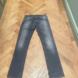 Nudie Jeans Mörkgrå - Snygga mörkgrå jeans med raka ben och klassisk femficksdesign. Jeansen har en lätt tvättad look och är perfekta för en avslappnad stil. Tillverkade i mjukt denimtyg som ger en skön känsla hela dagen.