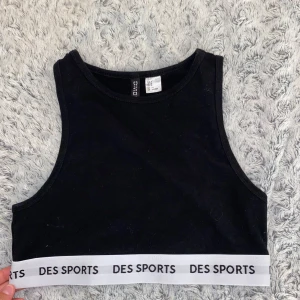 Svart crop top DES SPORTS - Säljer denna svarta sport toppen i typ linnetyg🤗 Använd fåtals gånger. Den når NÄSTAN ner till naveln 
