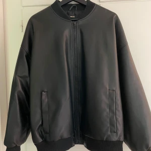 Svart bomberjacka från Bik Bok - Snygg svart bomberjacka från Bik Bok i skinnimitation med oversized passform. Tyvärr är ena fickan sönder, där av har jag sänkt priset. Vet ej fraktkostnaden.