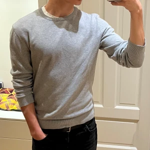 Grå stickad tröja - Säljer en stilren grå stickad tröja från Pier One. Tröjan har rund halsringning och ribbade muddar vid ärmslut och nederkant. Perfekt för lager-på-lager och passar till det mesta i garderoben. 100% bomull. Sparsamt använd. Skriv vid minsta fundering🤙