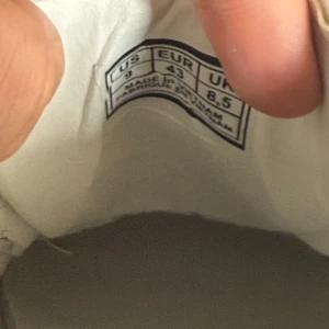 Alexander McQueen vita sneakers med svart häl - Säljer ett par klassiska vita sneakers från Alexander McQueen med svart hälparti och vit sula. Skorna har snörning och rund tå, samt tydlig logga på hälen och insidan. Perfekta för en stilren och modern look.