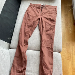 Bruna chinos från NN07 Marco - Säljer ett par bruna chinos från NN07, modell Marco, i italienskt bomullstyg. Byxorna har normal passform, dragkedja och knapp i midjan samt klassisk rak siluett. Perfekta för dig som vill ha en stilren och bekväm look.