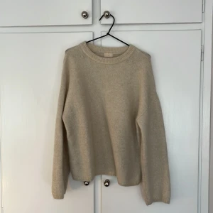 Beige stickad tröja från H&M - Mysig beige stickad tröja från H&M med rund halsringning och långa ärmar. Perfekt för lager-på-lager och enkel att matcha med olika outfits. Klassisk och stilren design.