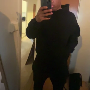 Svart hoodie från Essentials Fear of God - Säljer en svart hoodie från Essentials Fear of God. Tröjan har en klassisk passform med huva och tryckt logga både fram och bak. Perfekt för dig som gillar streetwear och vill ha en stilren look.