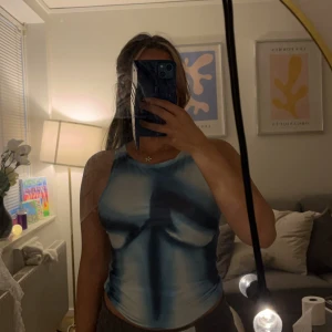 Blå och vit ärmlös linnetopp med tryck - Ärmlös linnetopp i blått och vitt med ett unikt tryck framtill som ger en edgy vibe. Mjukt material och rund halsringning🌸