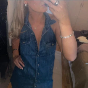 Jeansklänning - Snygg blå jeansklänning med halterneck och knappar i fram. Den saknar knappen längst upp men annars är den i bra skick! Nypris 600kr💙