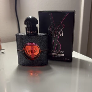 Black Opium Neon Eau de Parfum från Yves Saint Laurent - Säljer en Black Opium Neon Eau de Parfum från Yves Saint Laurent. Flaskan är svart med glittereffekt och har en rund rosa detalj i mitten där namnet står. Rymmer 30 ml och kommer i originalförpackning. Typ använt 6ml på den 