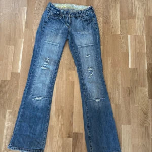 Blå bootcut jeans med slitningar - Säljer ett par sjukt snygga blå bootcut jeans med slitna detaljer. De har små slitningar längst ner men inget som märks tydligt eller stör 💓