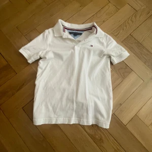 Vit pikétröja från Tommy Hilfiger - Säljer en klassisk vit pikétröja från Tommy Hilfiger skit get nu för sommaren. Inga fläckar eller defekter. Hör av dug om du undrar något!