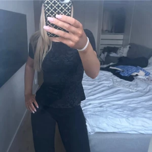 Svart mönstrad topp från Stockh LM - Säljer en svart topp från Stockh LM med vackert blommigt mönster. Toppen har korta ärmar och en figurnära passform. 