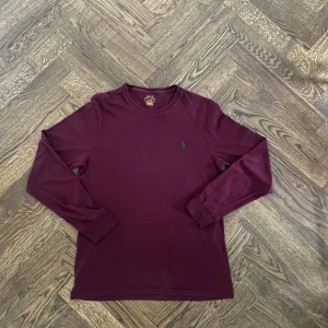 Vinröd långärmad tröja från Polo Ralph Lauren - Säljer en vinröd långärmad tröja från Polo Ralph Lauren med rund halsringning och den klassiska broderade loggan på bröstet. Perfekt för en stilren och avslappnad look. Nypris 1100