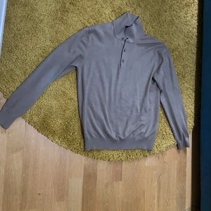 Beige långärmad pikétröja från Massimo Dutti - Säljer en stilren beige långärmad pikétröja från Massimo Dutti. Tröjan har klassisk krage med knäppning och är tillverkad i ett mjukt, tunt material som passar perfekt för lager-på-lager. Enkel och tidlös design. Pris går att förhandla 