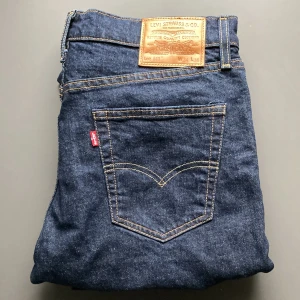Levi's 511 jeans i mörkblå denim - Säljer ett par klassiska Levi's 511 jeans i mörkblå denim. Modellen har en rak passform med fem fickor och tydliga kontrastsömmar. Ikonisk läderpatch bak i midjan och röd Levi's-tagg på bakfickan. (Testade fåtal gånger) | Säljer pågrund av returneringen tog slut| Hör av dig vid fundering 🤔 