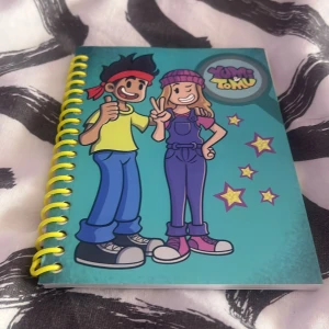 Yumi & Tomu - En färgglad anteckningsbok med tecknade figurer på omslaget, perfekt för att skriva ner idéer, tankar eller skisser. Spiralbunden och fylld med blanka sidor – ett måste för dig som gillar kreativitet och vill ha något unikt i väskan.