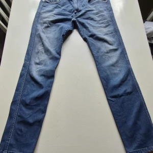Blå Replay jeansbyxor herr - Säljer ett par klassiska blå jeans från Replay med raka ben och fem fickor. Byxorna har normal passform och är tillverkade i slitstarkt denim med snygga detaljer och läderpatch bak i midjan. Perfekt för sommarkvällar! 