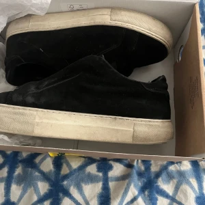  Axel Arigato 360 no laces med vit sula - Säljer ett par svarta sneakers med tjock vit sula. Skorna har en enkel och stilren design utan synliga loggor, och är tillverkade i mocka. Perfekta för dig som gillar minimalistisk stil.