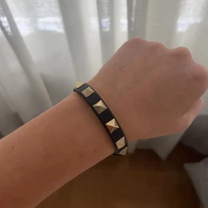 Svart armband från Valentino - Säljer ett svart armband från Valentino med guldfärgade nitar. Har knappt använt den och det finns inga defekter. 