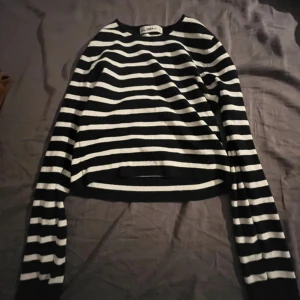Svartvit randig stickad tröja från Zara - Säljer en svart och vit randig stickad tröja från Zara. Tröjan har långa ärmar och en klassisk rund halsringning. Perfekt för dig som gillar enkel och stilren design.