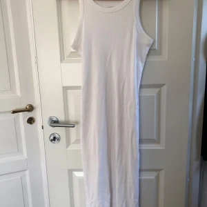 Vit ribbad långklänning - Säljer en vit ribbad långklänning från Lager157 i storlek S. Klänningen är ärmlös med rund halsringning och har en tight passform. Perfekt för sommardagar eller som ett basplagg i garderoben! 🤍