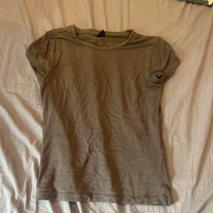 T shirt - En enkel mörkgrå t-shirt med rund halsringning och korta ärmar. Modellen är rak och passar perfekt till vardags. T-shirten är tillverkad i mjukt bomullsmaterial.