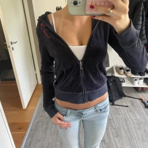 Mörkblå velour hoodie från Juicy Couture - Mysig mörkblå hoodie från Juicy Couture med dragkedja framtill och huva. Jackan har en croppad passform och ett stort rött kronmotiv samt logga på ryggen. Perfekt för en avslappnad och trendig look. Använd några få gånger ❣️