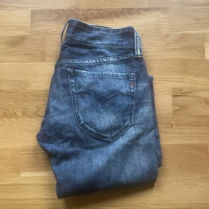 Replay jeans - Klassiska blå jeansbyxor från replay med raka ben och femficksdesign. Jeansen har slitna detaljer och en diskret replay -logga på bakfickan. Passar perfekt till en avslappnad stil. Midja 39cn 