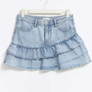 Ljusblå jeanskjol med volanger - Superfin ljusblå jeanskjol med två lager volanger och dragkedja och knapp i midjan. 