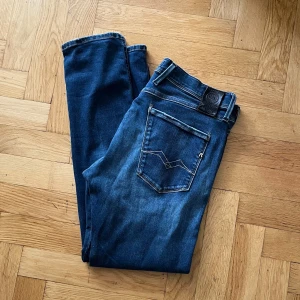 Replay Hyperflex Anbass jeans blå - Säljer ett par Replay Hyperflex Anbass jeans i klassisk blå tvätt. Jeansen har fem fickor, snygga slitningar och stretchigt material för extra komfort. Passformen är slim och modellen har raka ben. Perfekta för dig som gillar stilrena och bekväma jeans.