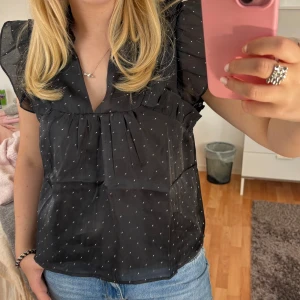 Svart prickig blus från Neo Noir - Supersöt svart blus från Neo Noir med små silver prickar och volangdetaljer på axlarna. Nyköpt med prislappen kvar! 💕 Storlek 38. 