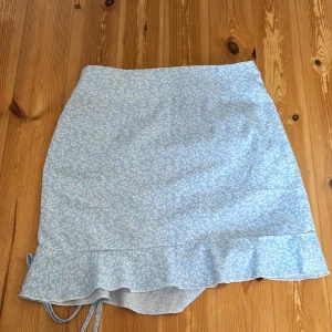 Kort kjol -  Kort blommig kjol med Scrunch vid sidan. Kjolen är blå och vit blommig med en dragkedja på sidan. Från shein och storlek XS. I bra och fint skick, använd fåtal gånger💖KAN ABSOLUT GÅ NER I PRIS VID SNABB AFFÄR ELLER BUNDLE!