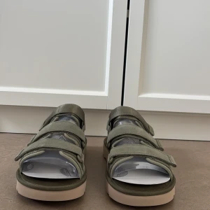 Olivgröna sandaler från UGG - Snygga olivgröna sandaler från UGG med tre justerbara kardborreband och chunky beige sula. Skorna har öppen tå och är tillverkade i textilmaterial, perfekta för varma dagar. UGG-logga på sulan. Riktigt bekväma och trendiga för sommaren. I storlek 42