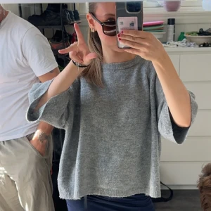 Grå stickad tröja med trekvartsärm - Mysig grå stickad tröja med avslappnad passform och trekvartsärmar. Tröjan har en enkel rund halsringning och är perfekt för lager-på-lager. Passar dig som gillar en chill och stilren look.