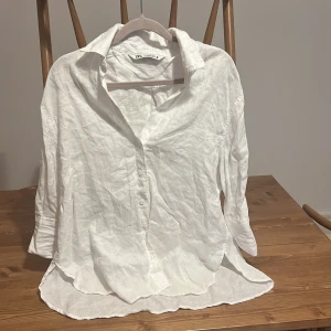 Vit linneskjorta - Säljer en vit skjorta från Zara i storlek XS. Skjortan är tillverkad i linne, har klassisk krage, knäppning framtill och långa ärmar. Perfekt oversized känsla och riktigt skön att bära under varmare dagar.