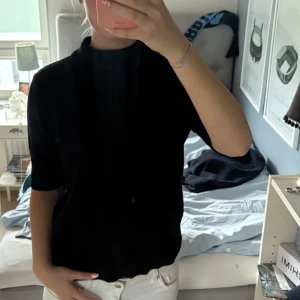 Svart polotröja med kort ärm - Säljer en svart polotröja med korta ärmar och hög hals. 