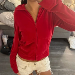 Röd velour hoodiejacka XS - Mysig röd hoodiejacka i mjuk velour från C. Jackan har dragkedja framtill, huva och fickor på sidorna. Perfekt för en chill och avslappnad stil. Snygg croppad passform och långa ärmar.
