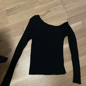 Svart ribbad offshoulder topp LCW XS - Svart långärmad topp från LCW Casual i ribbat stickat material. Snygg offshoulder-modell som ger en cool och trendig look. Perfekt att styla med jeans eller kjol för en enkel men stilren outfit.