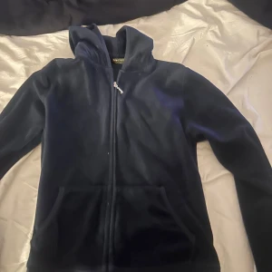 Mörkblå hoodie från Juicy Couture - Säljer min mörkblå tjocktröka från Juicy Couture med dragkedja och huva. Baksidan har ett stort, glittrigt Juicy Couture-tryck med en krona. Storlek L men liten i stl så passa som M