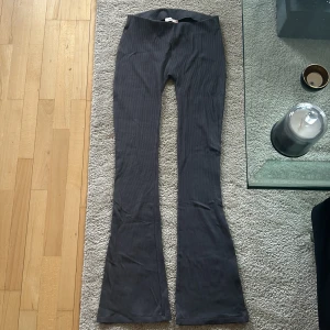 Grå ribbade byxor från Nelly - Snygga grå ribbade byxor från Nelly i storlek S. Byxorna har en hög midja och en bootcut-stil som ger en trendig look. Perfekta för en stilren outfit. 