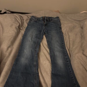 Blå utsvängda jeans - Snygga blå utsvängda jeans med dragkedja och knapp framtill. Perfekta för en avslappnad stil med en klassisk jeanslook. De har en lätt tvättad effekt som ger en cool vintagekänsla.🩷🥰