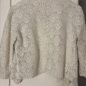 Vit spetsjacka från OBJECT - Säljer en elegant vit spetsjacka från OBJECT. Jackan har ett vackert spetsmönster och har inga defekter. Den är öppen framtill och har en mjuk och bekväm passform. 