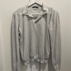 Grå polotröja från Brandy Melville - Säljer en stilren grå polotröja från Brandy Melville. Tröjan har långa ärmar och en klassisk krage med knappar framtill. Perfekt för en avslappnad och snygg look. Passar till många olika outfits! Endast använd ett fåtal gånger så i mycket bra skick! 