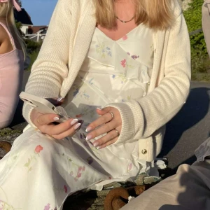 Vit blommig långklänning - Vit långklänning med blommigt mönster från Gina Tricot. Klänningen har en omlott-design och v-ringad hals. Perfekt för midsommar 🌸