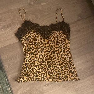 Leopardmönstrad linne med spetsdetaljer - Säljer en snygg leopardmönstrad linne med tunna axelband och spetsdetaljer vid halsringningen. 